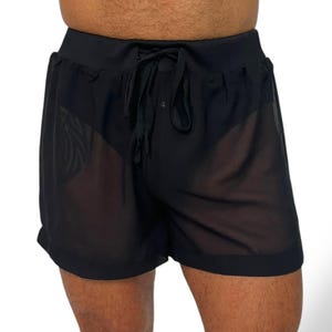 May include: Black sheer shorts with a drawstring waistband. The shorts are made of a lightweight, see-through fabric. The shorts have a relaxed fit and are suitable for swimwear or casual wear.