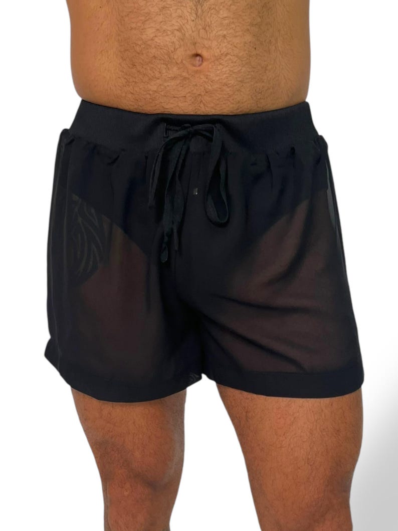 May include: Black sheer shorts with a drawstring waistband. The shorts are made of a lightweight, see-through fabric. The shorts have a relaxed fit and are suitable for swimwear or casual wear.
