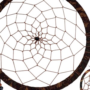 May include: A brown dreamcatcher with a patterned fabric border and black beads hanging from the bottom. The dreamcatcher is circular in shape and has a web-like design in the centre.