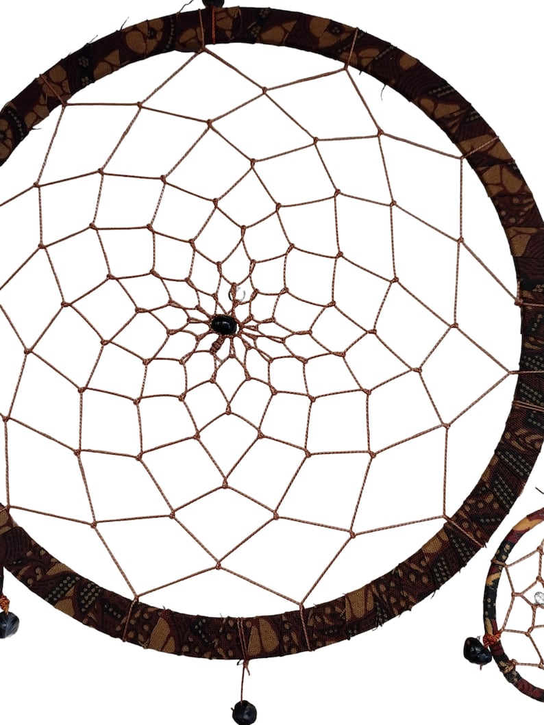 May include: A brown dreamcatcher with a patterned fabric border and black beads hanging from the bottom. The dreamcatcher is circular in shape and has a web-like design in the centre.