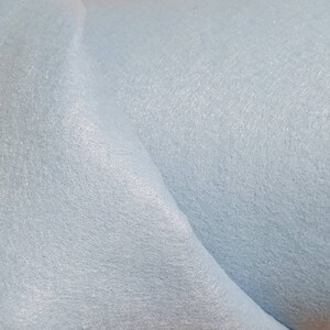 May include: A close-up of a light blue fabric with a soft, textured surface.