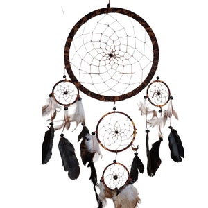 May include: A brown and black dreamcatcher with multiple layers of netting and feathers. The dreamcatcher has a beaded fringe and is decorated with a floral pattern.
