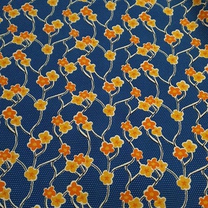 May include: Blue fabric with a repeating pattern of orange and yellow flowers on white stems. The background is a blue fabric with tiny white dots.