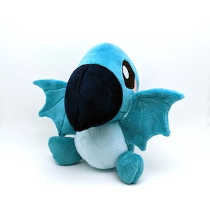 May include: A blue plush toy with wings, a large beak, and big eyes. The toy is made of soft, fuzzy fabric and has a light blue belly.
