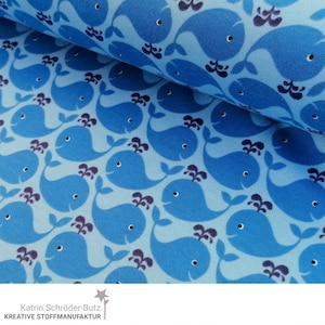Könnte beinhalten: Blauer Stoff mit einem sich wiederholenden Muster aus hellblauen Walen mit dunkelblauen Akzenten. Der Stoff hat eine dezente Textur und einen hellblauen Hintergrund.
