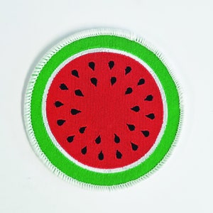 May include: A round, white-edged patch with a green outer ring and a red watermelon slice in the center. The watermelon slice has black seeds.