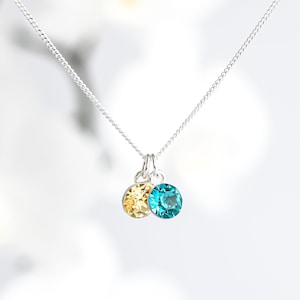 May include: A silver chain necklace with a small pendant featuring two round crystals, one turquoise blue and one yellow.
