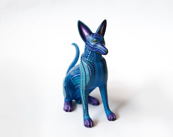 May include: A blue and purple wooden carved dog figurine with intricate details. The dog is sitting with its head turned to the side and its tail curled behind it.