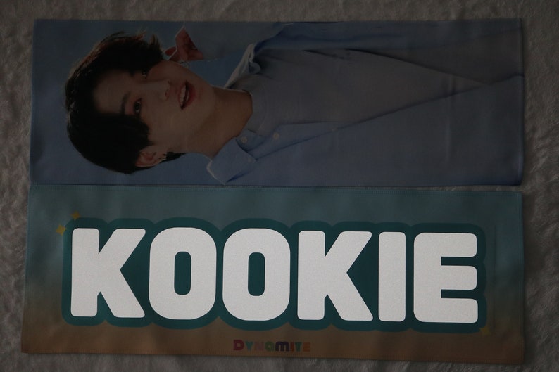 May include: A blue and white banner with the word "KOOKIE" in white letters on a teal background. The banner also has a small yellow star and the word "Dynamite" in white letters on a blue background.
