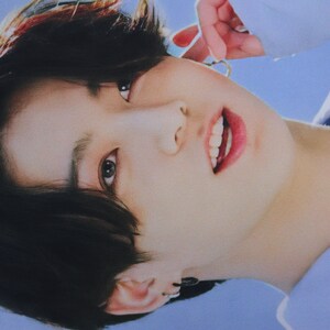 May include: A close-up of a person's face with dark hair, wearing a light blue shirt. The person is smiling and looking at the camera.