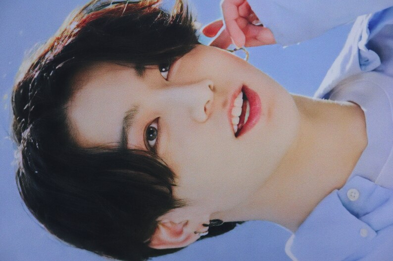 May include: A close-up of a person's face with dark hair, wearing a light blue shirt. The person is smiling and looking at the camera.