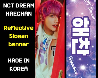 Puede incluir: Una pancarta reflectante con el texto "NCT Dream Haechan" en letras blancas sobre un fondo morado con un patrón de corazones. La parte delantera de la pancarta presenta una foto de una persona con el pelo rosa. La parte trasera de la pancarta tiene el texto "해찬" en letras blancas sobre un fondo morado con un patrón de corazones.