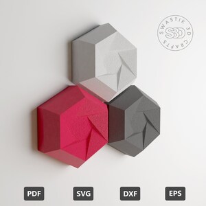 Op de afbeelding: Drie geometrische wanddecoraties in grijs, rood en zwart. Elk stuk is zeshoekig met een textuur. De stukken zijn in een driehoekige vorm gerangschikt. De afbeelding bevat de tekst "Swastik 3D Crafts".