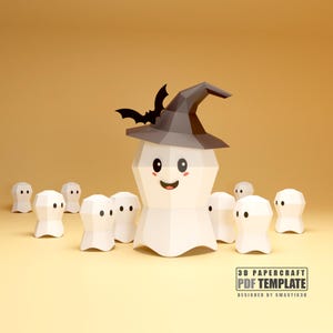 Op de afbeelding: Een 3D-papierknutselontwerp met Halloween-thema met een lachend spook met een heksenhoed en een vleermuis. Kleinere spookfiguren omringen de hoofdfiguur. Het ontwerp staat tegen een warme, gele achtergrond.