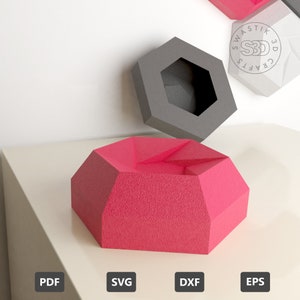 Op de afbeelding: Een roze geometrisch gevormde kom met een textuur. De kom is gemaakt van 3D-geprint materiaal. De afbeelding toont ook een grijze geometrisch gevormde kom.