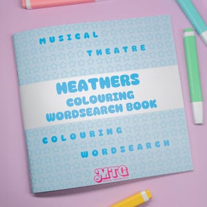 K&ouml;nnte beinhalten: Ein "Heathers" Mal- und Suchselbuch mit dem Text "Musical Theatre" in Hellblau. Das Buch hat einen hellblauen Sternmusterhintergrund und den Text "Colouring Wordsearch Book". Das Logo "MTC Musical Theatre Gifts" befindet sich unten.