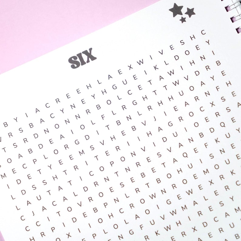 May include: A spiral-bound word search puzzle book with the word "SIX" in gray block letters at the top. The pages are filled with a grid of letters, and two star graphics are in the upper right corner.