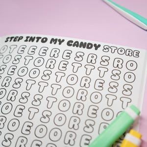 K&ouml;nnte beinhalten: Ein Wortsuchr&auml;tselbuch mit dem Text "STEP INTO MY CANDY STORE" oben. Das R&auml;tsel ist mit Buchstaben gef&uuml;llt, und ein gr&uuml;ner und wei&szlig;er Textmarker befindet sich in der unteren rechten Ecke. Der Hintergrund ist hellviolett.