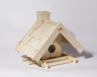 Op de afbeelding: Een houten vogelhuisje met een pannendak en een kleine schoorsteen. Het vogelhuisje heeft een ronde opening en een voederbak. De natuurlijke houtkleur geeft het een rustieke uitstraling. Het vogelhuisje is ontworpen om vogels aan te trekken.