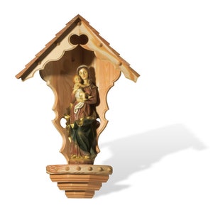 Puede incluir: Un santuario de madera con un techo tallado y una peque&ntilde;a estatua de la Virgen Mar&iacute;a sosteniendo un beb&eacute; Jes&uacute;s en su interior.