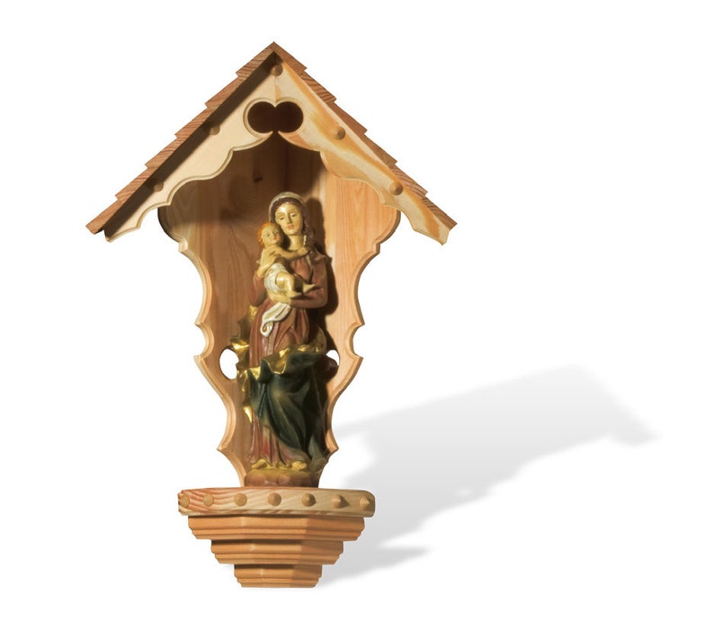 Puede incluir: Un santuario de madera con un techo tallado y una peque&ntilde;a estatua de la Virgen Mar&iacute;a sosteniendo un beb&eacute; Jes&uacute;s en su interior.
