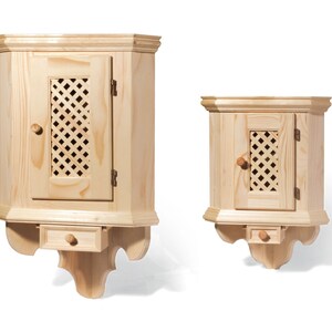 Puede incluir: Dos armarios de esquina de madera con una sola puerta y un peque&ntilde;o caj&oacute;n debajo. Los armarios son de madera clara y tienen un dise&ntilde;o simple y tradicional.