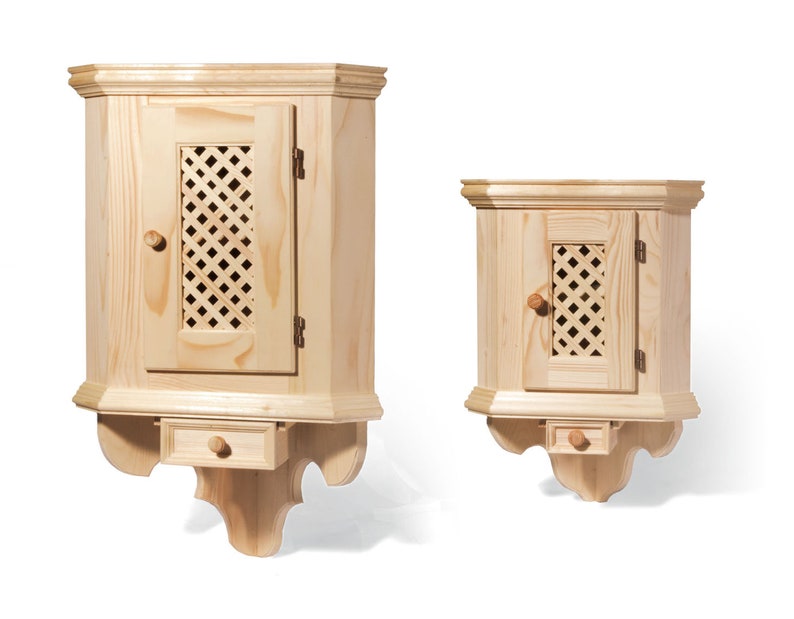 Puede incluir: Dos armarios de esquina de madera con una sola puerta y un peque&ntilde;o caj&oacute;n debajo. Los armarios son de madera clara y tienen un dise&ntilde;o simple y tradicional.