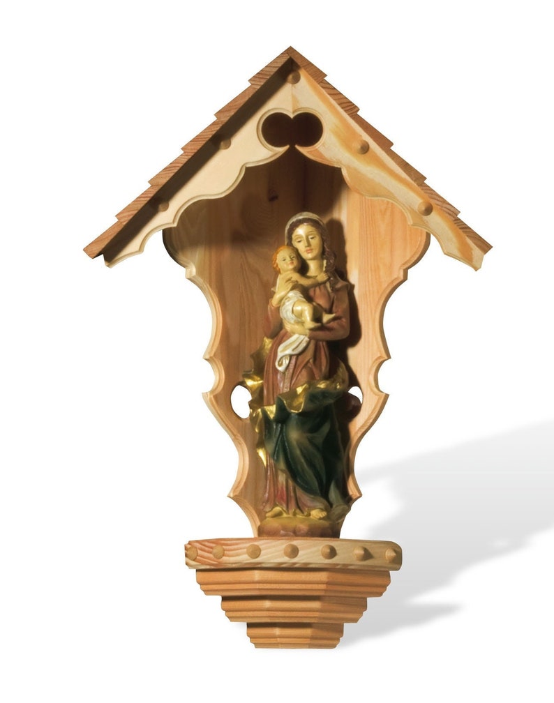 Puede incluir: Un nicho de pared de madera con un dise&ntilde;o tallado y ornamentado. El nicho presenta una estatua de la Virgen Mar&iacute;a sosteniendo un beb&eacute; Jes&uacute;s. La estatua est&aacute; hecha de madera pintada y tiene una apariencia realista.