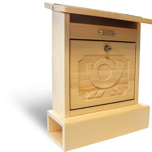 Puede incluir: Un buz&oacute;n de madera con una tapa abatible y un dise&ntilde;o de caracol tallado. El buz&oacute;n tiene un peque&ntilde;o caj&oacute;n y una cerradura. El buz&oacute;n est&aacute; montado sobre una base de madera.