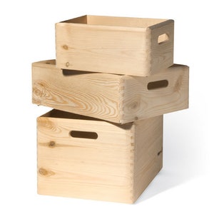 Op de afbeelding: Drie houten opbergdozen die op elkaar gestapeld zijn. De dozen zijn gemaakt van natuurlijk hout en hebben een rustieke uitstraling. De bovenste doos is de kleinste, de middelste doos is de grootste en de onderste doos is er tussenin. Alle drie dozen hebben handvatten aan de zijkanten.