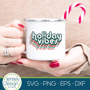 May include: A white enamel mug with a green, red, and white retro-style graphic that says "holiday vibes".