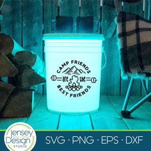 Pu&ograve; includere: Un secchio bianco con una grafica nera che dice "Camp Friends are the Best Friends" con un fal&ograve; e montagne nel design. Il secchio &egrave; illuminato dall'interno con una luce blu.