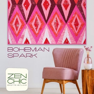 May include: A quilt pattern called "Bohemian Spark" by Zen Chic, featuring a geometric design of pink, red, and white diamonds. The quilt is displayed on a wall above a pink armchair and a wooden side table.