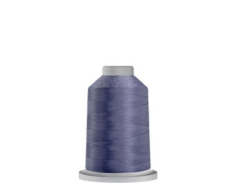 May include: A spool of blue-grey thread, tightly wound and cylindrical, sits on a white base. The thread has a subtle sheen, suggesting a smooth texture. The top of the spool is a lighter grey color.