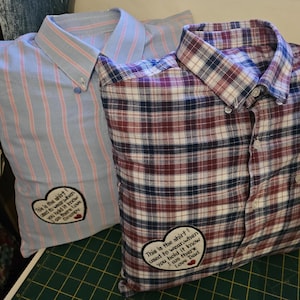 Puede incluir: Dos fundas de almohada hechas con camisas reutilizadas. La funda de almohada a rayas azul y rosa tiene un parche en forma de coraz&oacute;n con el texto "This is the shirt I used to wear when you held it know I am there Love Dad". La funda de almohada a cuadros rojo, azul y blanco tiene un parche en forma de coraz&oacute;n con el texto "This is the shirt I used to wear when you held it know I am there Love Dad".
