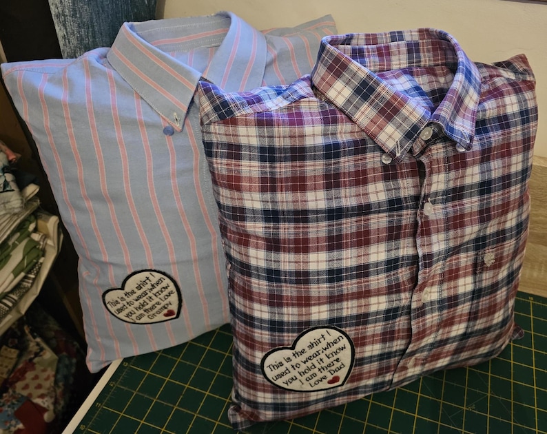 Puede incluir: Dos fundas de almohada hechas con camisas reutilizadas. La funda de almohada a rayas azul y rosa tiene un parche en forma de coraz&oacute;n con el texto "This is the shirt I used to wear when you held it know I am there Love Dad". La funda de almohada a cuadros rojo, azul y blanco tiene un parche en forma de coraz&oacute;n con el texto "This is the shirt I used to wear when you held it know I am there Love Dad".