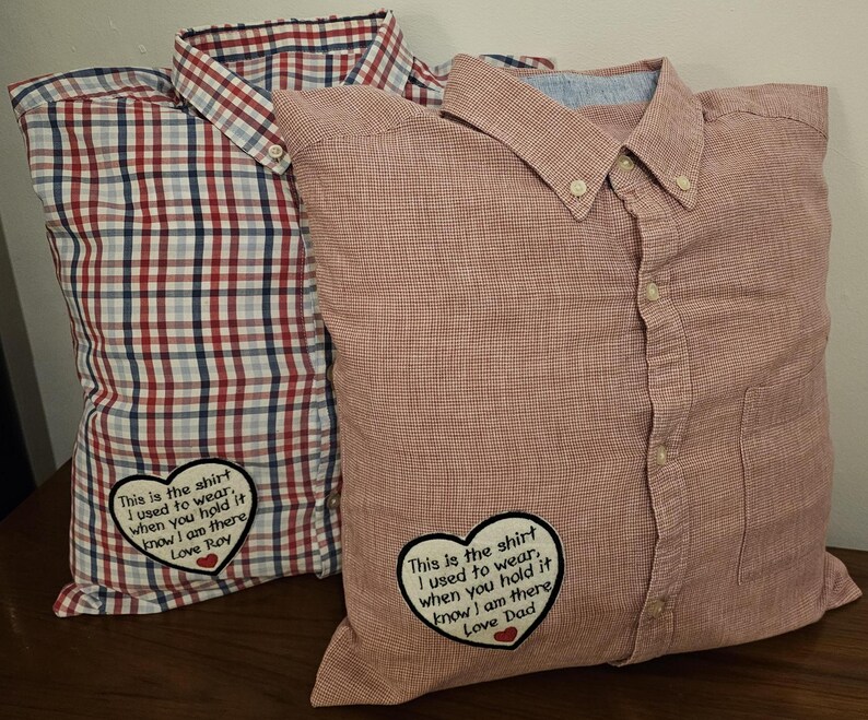Puede incluir: Dos fundas de almohada de cuadros rojos y blancos con corazones bordados y mensajes. Los mensajes dicen "This is the shirt I used to wear. When you hold it know I am there Love Roy" y "This is the shirt I used to wear. When you hold it know I am there Love Dad".
