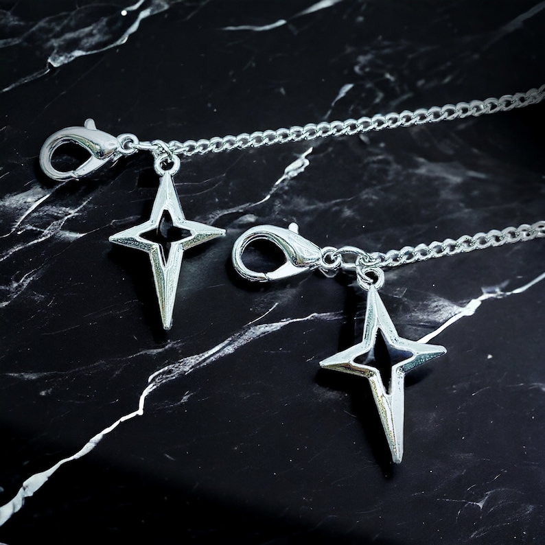 May include: Two silver chains with star-shaped charms. Each chain has a lobster clasp.