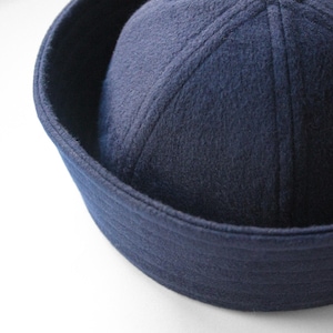 May include: A navy blue sailor hat with a rounded crown and a flat brim. The hat is made of a soft, felt-like material and features stitched details on the crown. The hat is a classic style, often associated with nautical themes.