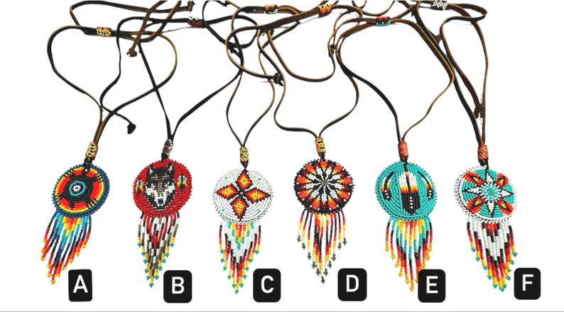 May include: Six beaded necklaces with different designs, including a wolf, feathers, and geometric patterns. Each necklace has a round pendant with a fringe of beads. The necklaces are labelled A through F.