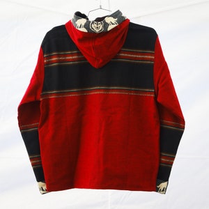May include: Red hooded sweatshirt with black and brown striped pattern and wolf design on the hood.