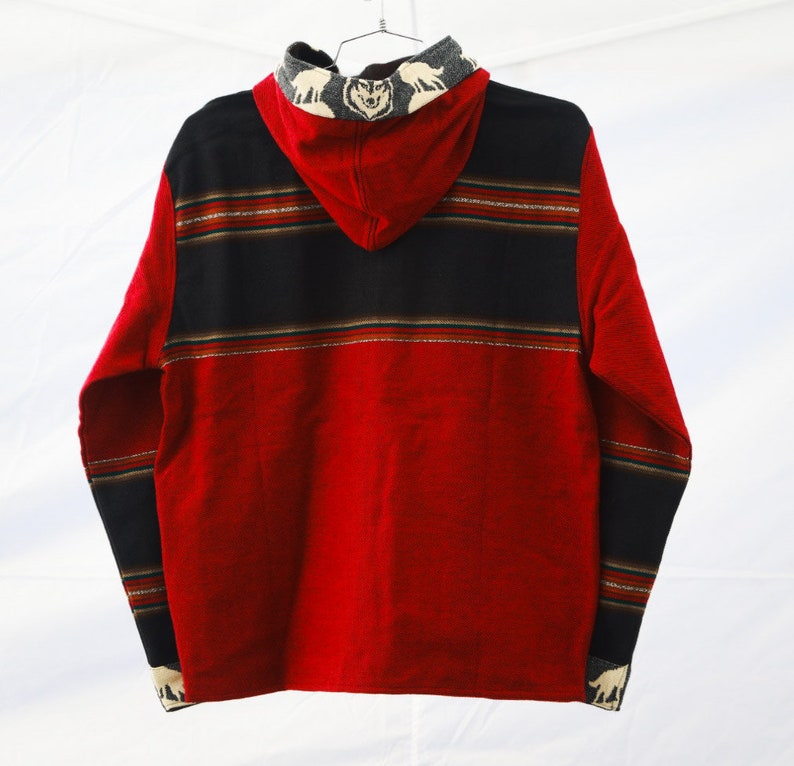 May include: Red hooded sweatshirt with black and brown striped pattern and wolf design on the hood.