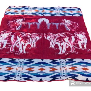 May include: Red and blue patterned throw blanket with a design of wolves howling at the moon.