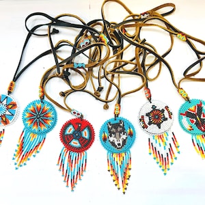 May include: Seven beaded necklaces with colourful, geometric patterns and fringe. Each necklace features a different design, including a star, a wolf, a turtle, and a bird. The necklaces are made with leather cords and beads in shades of blue, red, white, and yellow.
