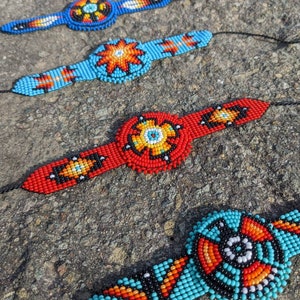 May include: Four beaded bracelets with colorful geometric patterns. Each bracelet features a central circular design with a variety of colors, including red, blue, orange, yellow, black, and white.