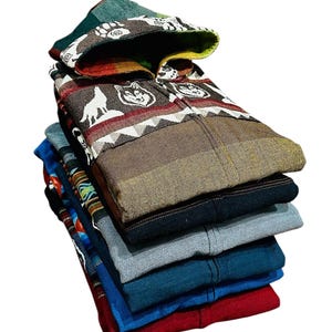 May include: A stack of six hooded shirts in various colors and patterns, including a brown shirt with a wolf design, a blue shirt with a geometric pattern, and a red shirt.