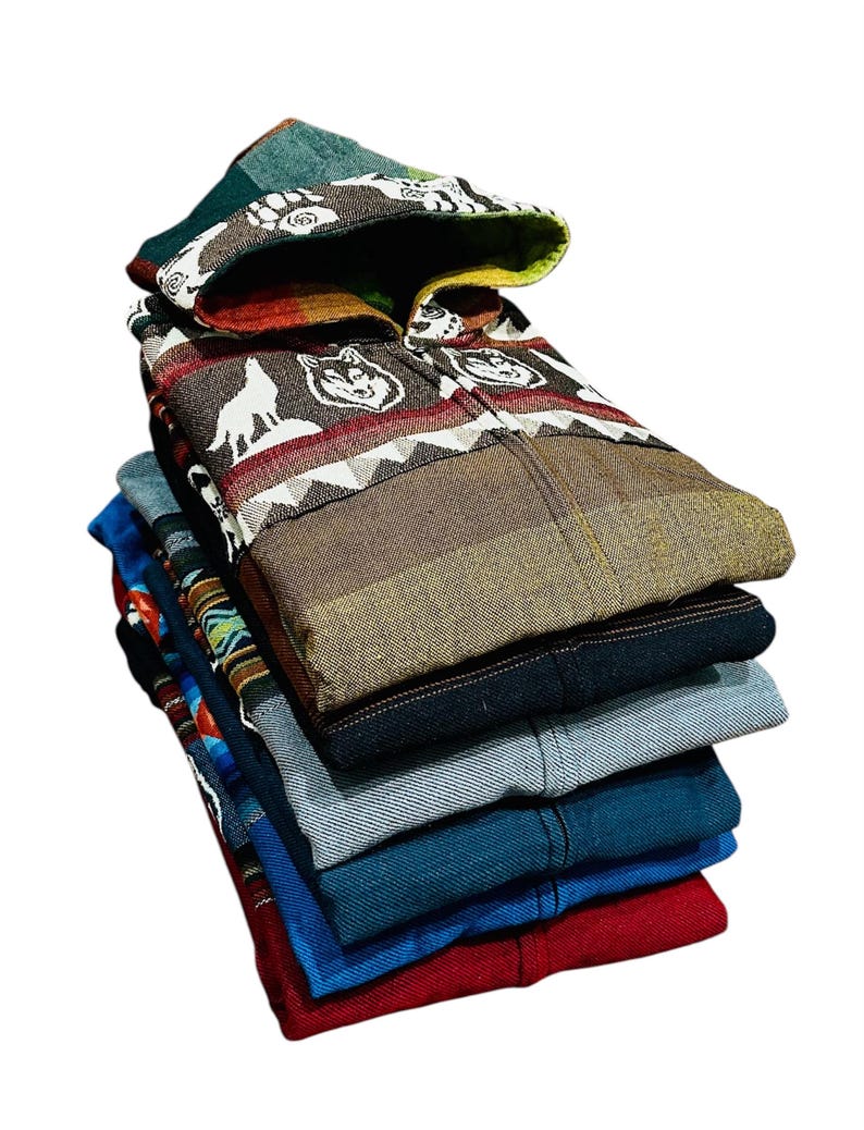 May include: A stack of six hooded shirts in various colors and patterns, including a brown shirt with a wolf design, a blue shirt with a geometric pattern, and a red shirt.