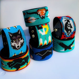 May include: Six beaded bracelets with different designs, including a wolf, an eagle, and a geometric pattern. The bracelets are made with colorful beads and leather.