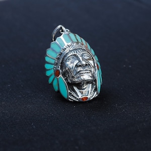 May include: Silver pendant featuring a detailed Native American chief bust with turquoise and red accents. The chief is wearing a headdress with feathers.
