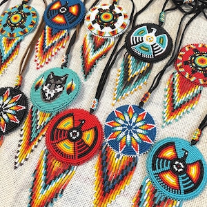 Op de afbeelding: Een verzameling van kralen Native American dreamcatchers met kleurrijke geometrische patronen en franjes. De dreamcatchers zijn gemaakt met turquoise, rode, gele, witte en zwarte kralen.